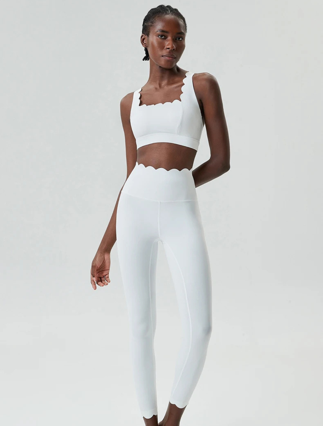 Mulher usando o Conjunto Fit Lizzy branco, composto por top e legging de cintura alta com detalhes ondulados. Design elegante e ajustado ao corpo, ideal para treinos e uso casual.






